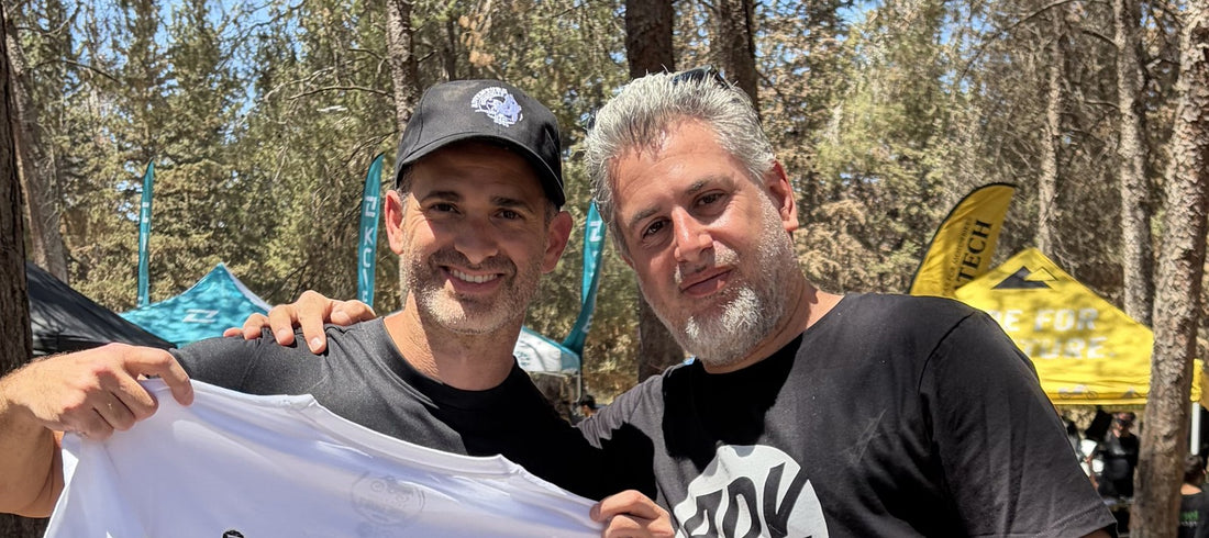 David holding up a white ADVTEES adventure motorcycle t-shirt with a fellow rider at a bike meet
